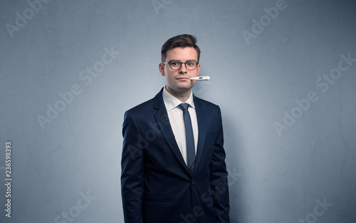 Young tired businessman with thermometer and copy space 