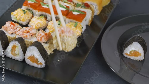 Top view on traditional japanese empty square black slate plate framed with sushi, ginger, soy, wasabi bowls, green leaves and chopsticks on rustic grey backround photo