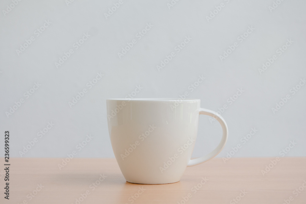 White coffee cup on wood table with copy space on white wall background. White coffee cup on wood table with copy space on white wall background.
