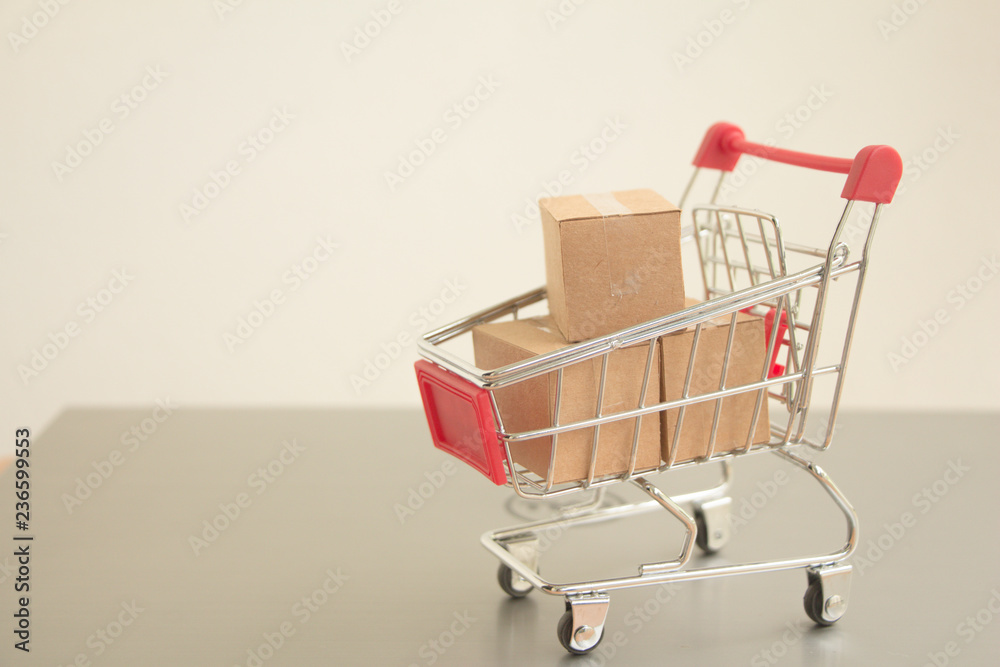 Miniature shopping cart with parcel or paper cartons in trolley on laptop,E-commerce concept.