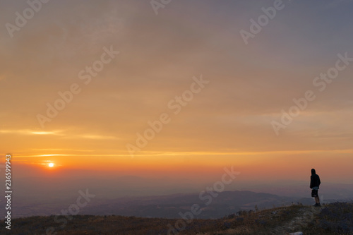 Silhouette of man watching the sunset from the top of a mountain