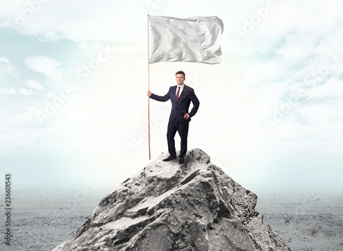 Handsome businessman on the top of the mountain with white flag 