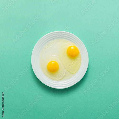 Egg crack and yolk in plate on green background, top view, flat lay