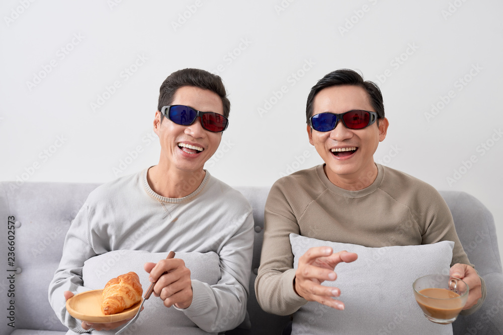 Exciting two asian men watch three-dimensional LCD TV with eye glass in a living room Exciting two asian men watch three-dimensional LCD TV with eye glass in a living room