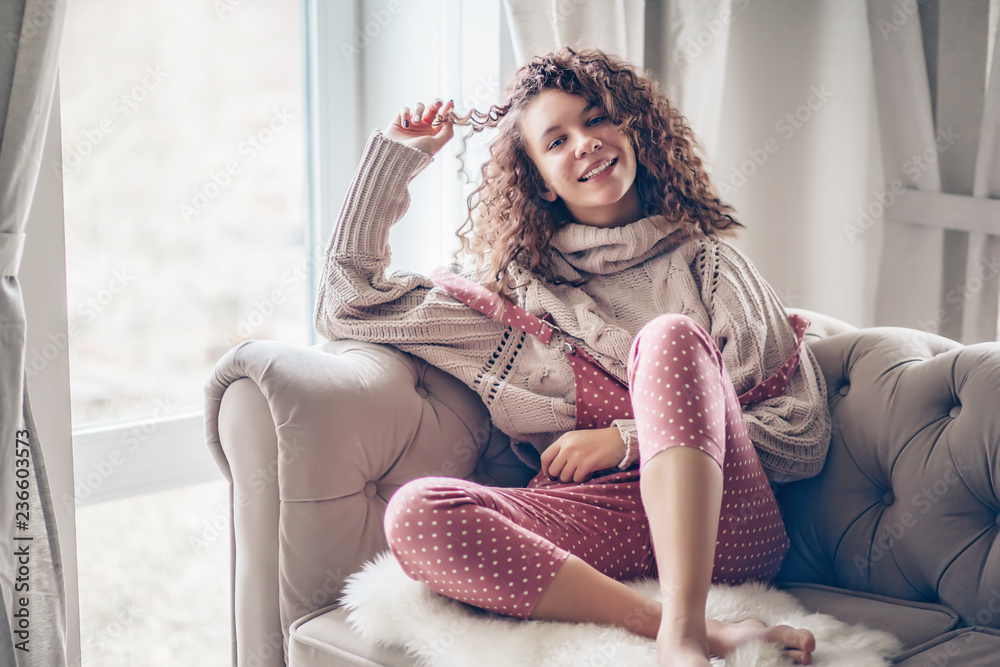 Teenage girl in sweater and jumpsuit on a couch Teenage girl in sweater and jumpsuit on a couch