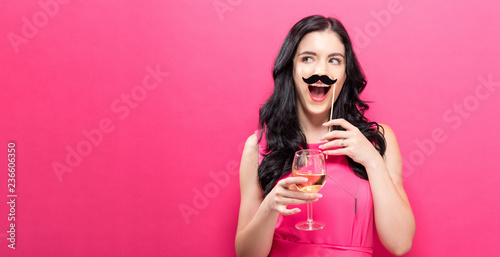Young woman holding champagne flute and paper party stick
