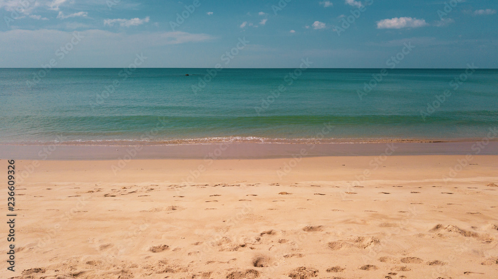 Tropical sandy beach view with blue sea ocean water over summer sky background during sunny day. Summer and travel vacation concept