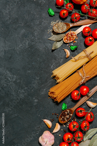 Italian food concept. Different kinds of pasta with ingredients, tomato, garlic, parsley, Bay leaf, pepper on a black background flat lay and copy space.