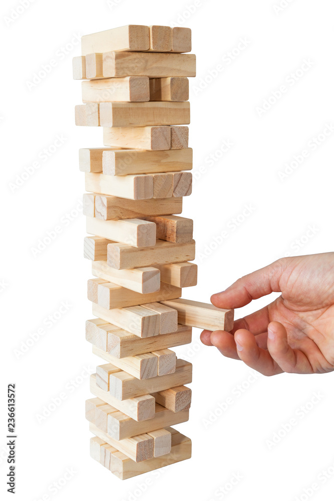Man's hand taking or putting a block to an unstable and incomplete tower of wooden blocks. Concept photo of planning, taking risks and strategizing. Isolated on white background. Man's hand taking or putting a block to an unstable and incomplete tower of wooden blocks. Concept photo of planning, taking risks and strategizing. Isolated on white background.