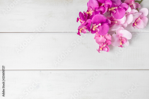 Tela Artificial orchids on white wooden background.