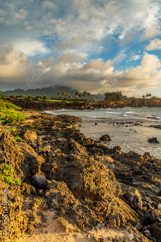 Waves Breaking into Makawehi Bluff while warm sunrise light illuminates the clouds, Kauai, Hawaii