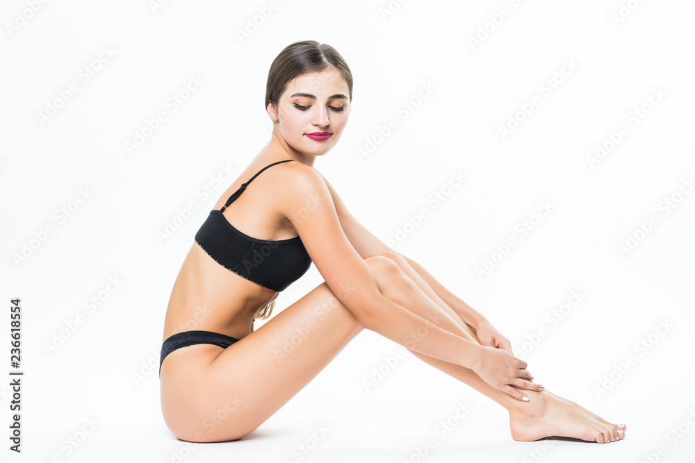 Young woman with slim body in lingerie, isolated on white background. Cosmetics, healthcare.