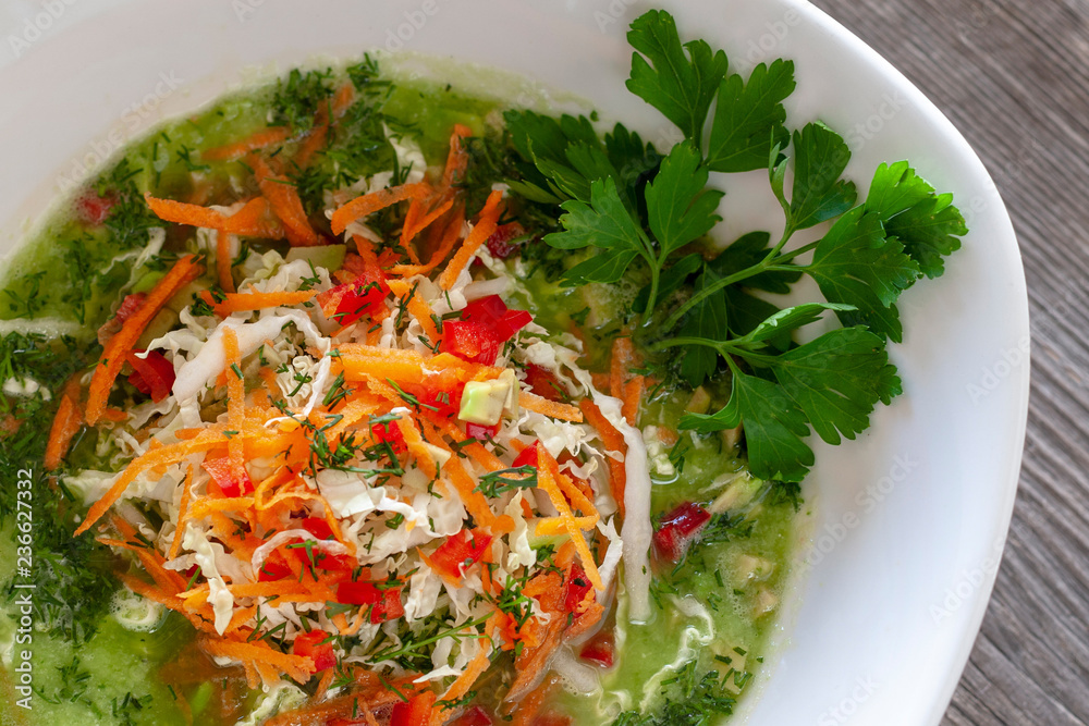 Vegetarian dish. Vegan green cabbage soup made from Chinese cabbage, carrots, peppers, tomatoes, avocados, pumpkin seeds and lemon juice, garnished with parsley. Vegetarian dish. Vegan green cabbage soup made from Chinese cabbage, carrots, peppers, tomatoes, avocados, pumpkin seeds and lemon juice, garnished with parsley.