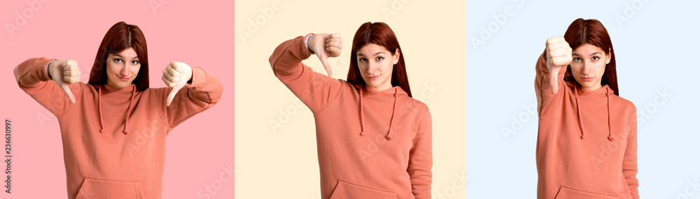 Set of Young redhead girl with pink sweatshirt showing thumb down sign with negative expression. Sad expression on colorful background Set of Young redhead girl with pink sweatshirt showing thumb down sign with negative expression. Sad expression on colorful background