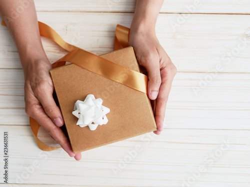 hands taking off  gift box ribbon bow on woodtop copy space  photo