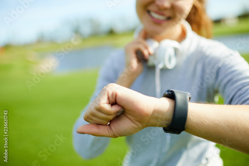 Young active female looking at watch on her wrist while checking time of training