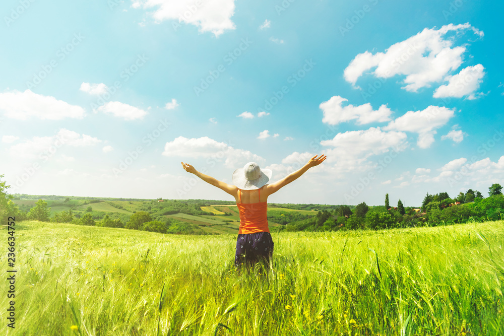 Beautiful young girl enjoying hot summer day in the middle of the field of hops with hands wide open and big white hat Beautiful young girl enjoying hot summer day in the middle of the field of hops with hands wide open and big white hat