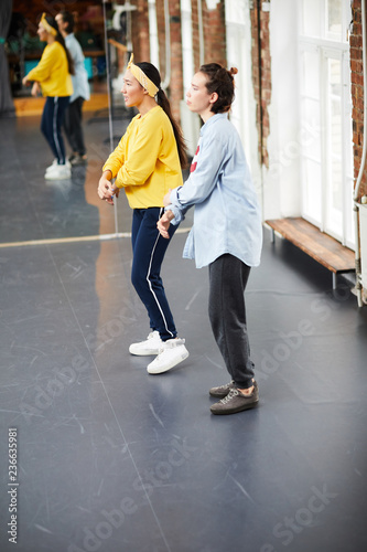 Two active girls training by large mirror in modern studio of hip hop dancing