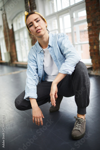 Young woman in activewear squatting in studio of modern dancing in front of camera