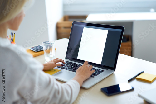 Young woman typing on laptop while working in home office