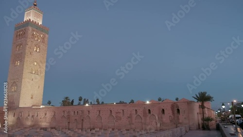 Dusk camera pan left to reveal tastefully lighted Koutoubia Mosque minaret and old mosque ruins site in Marrakech, Morocco photo