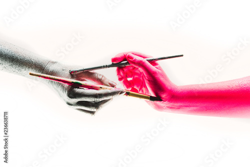 Unity in diversity. Concept of showing different people taking each others features. Close up of two hands holding paintbrush and coloring each other. Meeting and symbiosis of human beings. photo