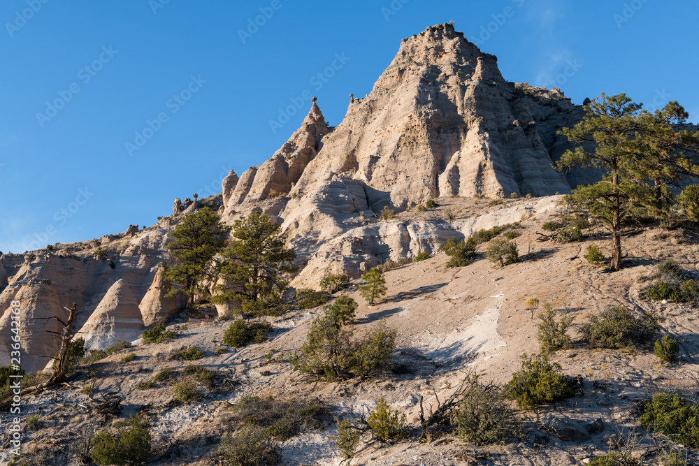 Fototapeta premium High, steep mountain peak with hoodoo rock formations and ponderosa pine trees at Kasha-Katuwe Tent Rocks National Monument, New Mexico