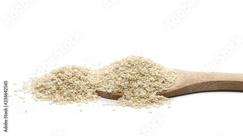 Pile sesame seeds and wooden spoon isolated on white