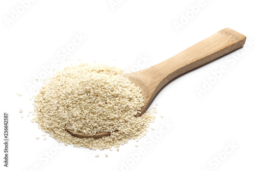 Pile sesame seeds and wooden spoon isolated on white
