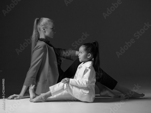 Young mother with her little daughter are posing in studio.