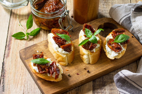 Italian Antipasti snacks for Wine. Brushetta with Soft Cheese and Dried Tomatoes on a wooden table.