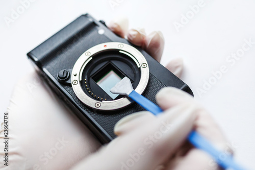 Close-up of mirrorless digital APS-C dirty camera matrix sensor cleaning and maintenance with swab, photographer cleaning photocamera on white background photo