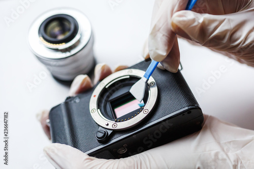 Close-up of mirrorless digital APS-C dirty camera matrix sensor cleaning and maintenance with swab, photographer cleaning photocamera on white background photo