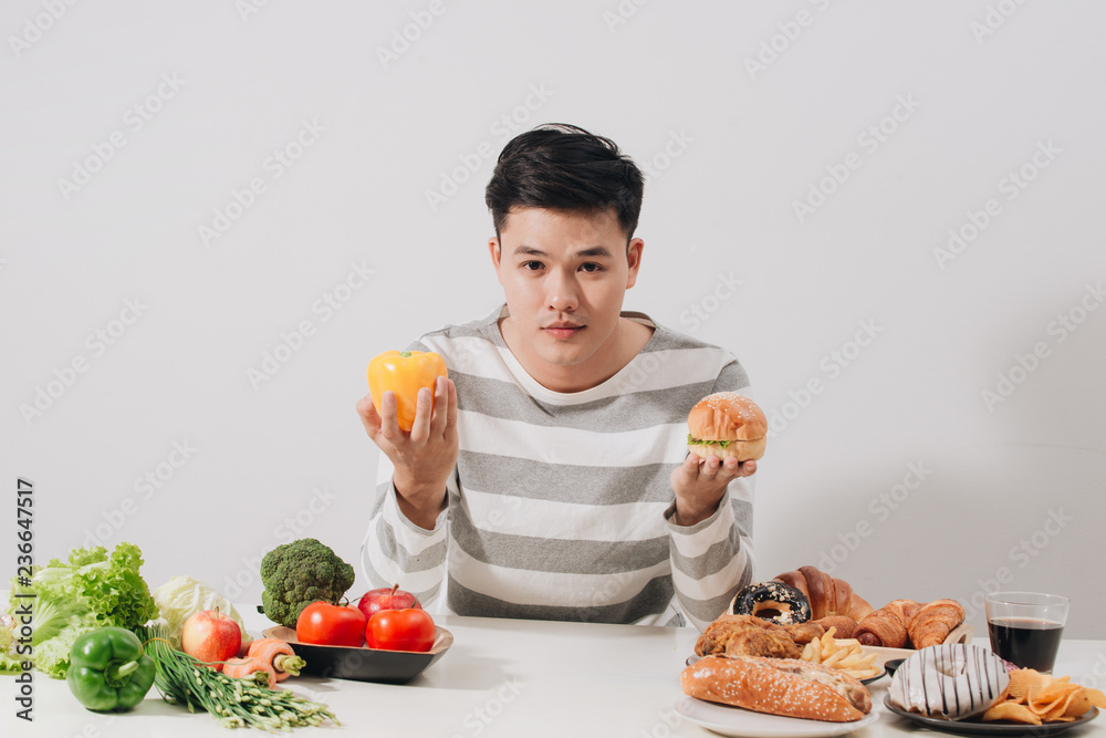 Man having hard choice between healthy and unhealthy food Man having hard choice between healthy and unhealthy food