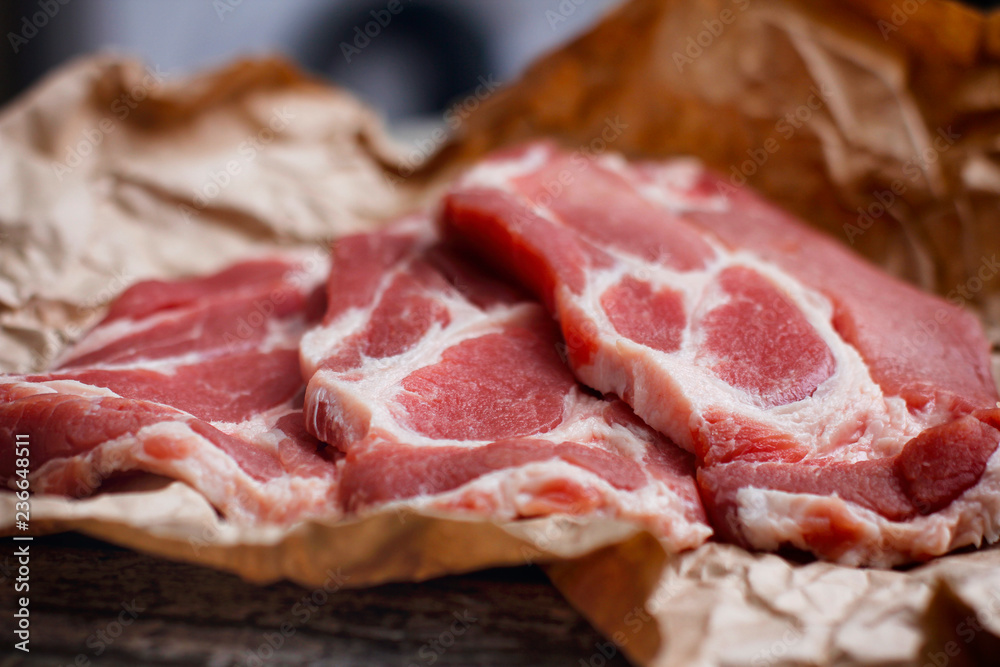 Fresh raw sliced meat on cooking paper and wooden table. Fresh raw sliced meat on cooking paper and wooden table.