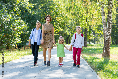 Happy young family, mother with three children walking in the park. Healthy lifestyle concept
