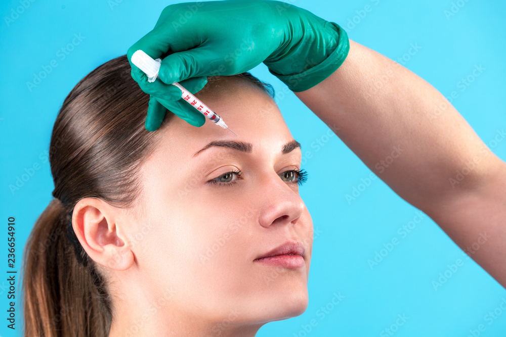 Fototapeta premium Beautiful woman face and beautician hands with syringe. Doctor makes cosmetic injection. Clean Beauty concept