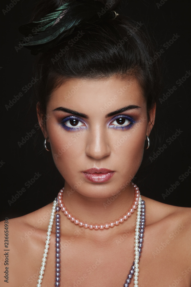 Portrait of young beautiful brunette with stylish make-up and feather in her hair