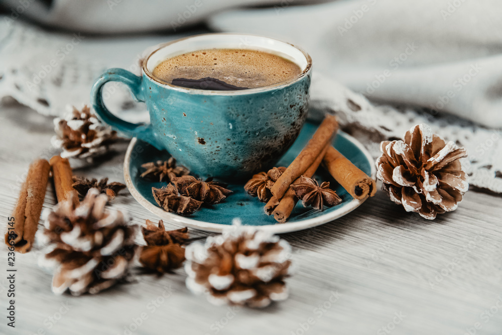 turquoise cup of hot coffee with cinnamon sticks on grey background