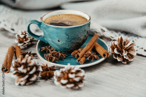 turquoise cup of hot coffee with cinnamon sticks on grey background © Maria