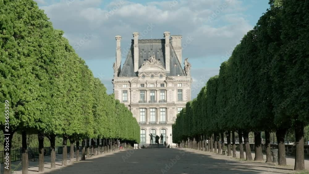 Camera still view through rows of trees to the Ecole du Louvre on the Terrasse du Bord de l'Eau near Tuileries Garden in Paris, France