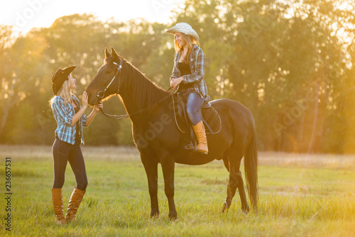 Girl equestrian rider stands near the horse. Girl equestrian rider riding a beautiful horse in the rays of the setting sun. Horse theme 