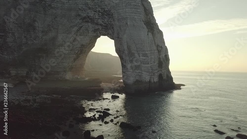 Sunset and natural arch with cliffs and sea - drone footage