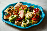 old blue tray with a set of healthy tapas or mini sandwiches on a light wooden table