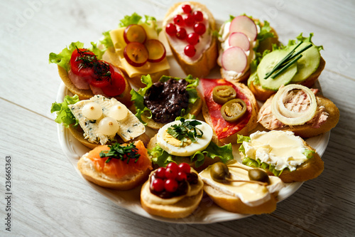 plate with colorful and healthy sandwiches or tapas on a light wooden table