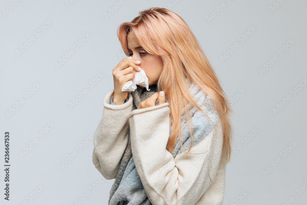 Cute sick young woman with strawberry blonde hair sneezing or using handkerchieif to wipe snot from her nose. Rhinitis, cold, sickness, allergy concept. Flu epidemic Cute sick young woman with strawberry blonde hair sneezing or using handkerchieif to wipe snot from her nose. Rhinitis, cold, sickness, allergy concept. Flu epidemic