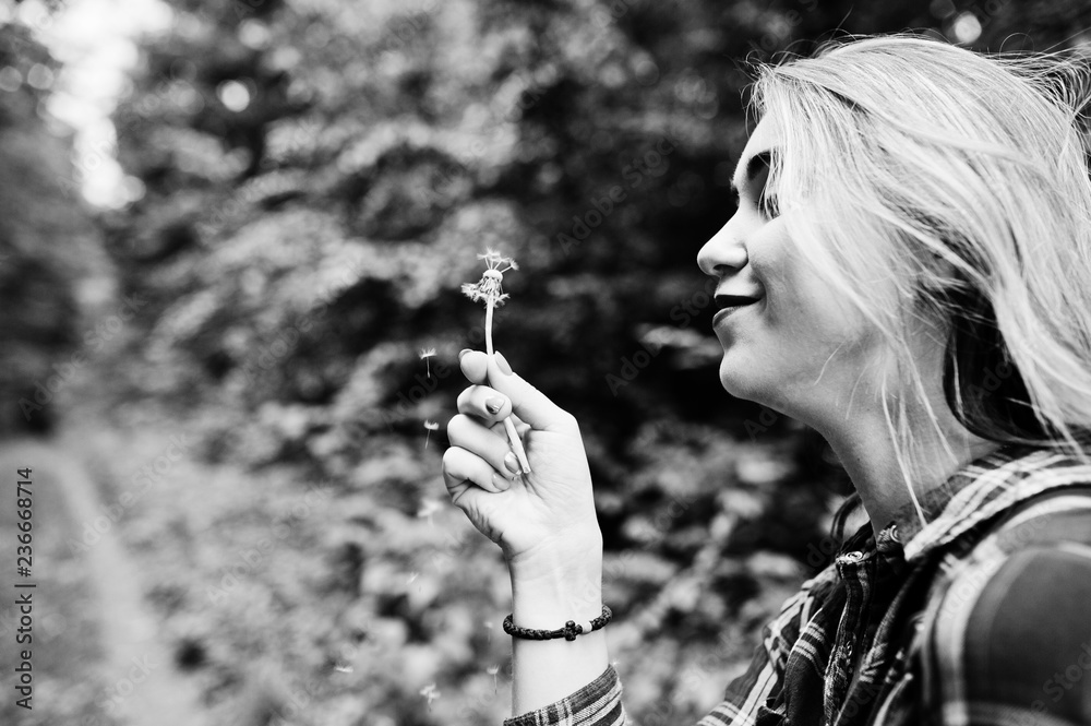 Close-up portrait of a blond girl in tartan shirt blowing dandelion. Close-up portrait of a blond girl in tartan shirt blowing dandelion.