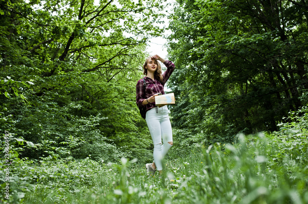 Portrait of a young beautiful blond woman in tartan shirt holding a map in the forest. Portrait of a young beautiful blond woman in tartan shirt holding a map in the forest.