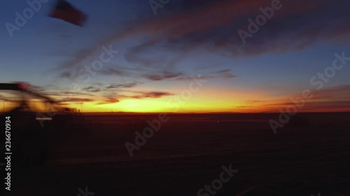 Deep red sunset in the desert with dune buggies driving by