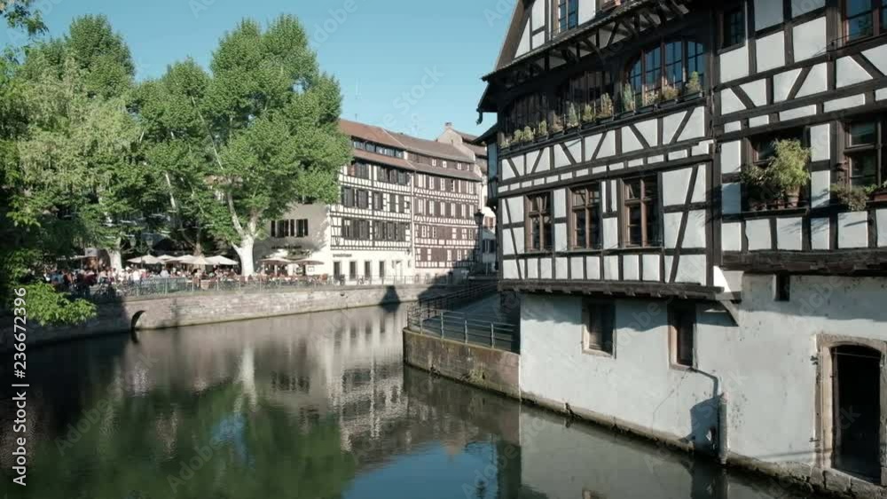 Camera track right view over Ill River, waterfront Place Benjamin Zix square and traditional old town houses of Petite France crossing Pont Du Faisan drawbridge in Strasbourg, France